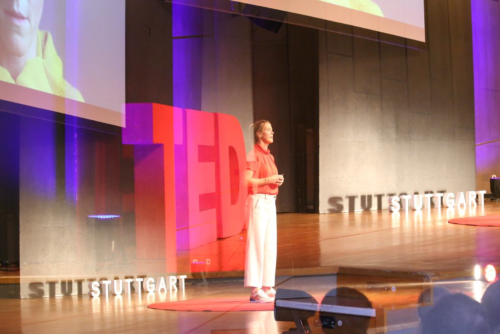 Eine Speakerin auf der Bühne beim TEDxStuttgart 2023. Das Bild ist mit Spiegel-Effekten etwas verfremdet.